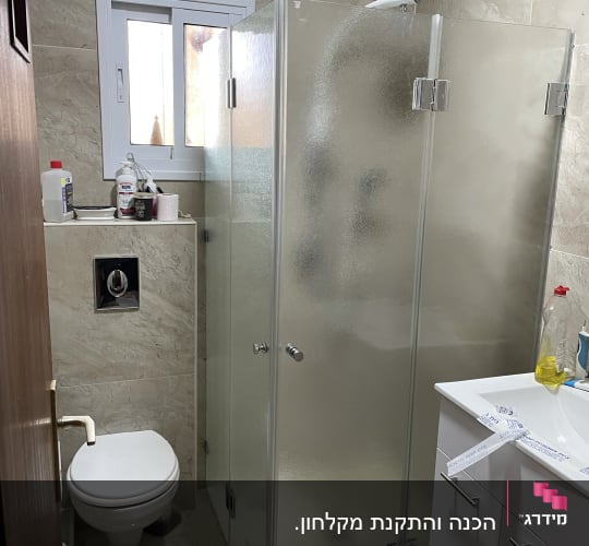 מקלחון זכוכית עם דלתות מתכת בחדר אמבטיה